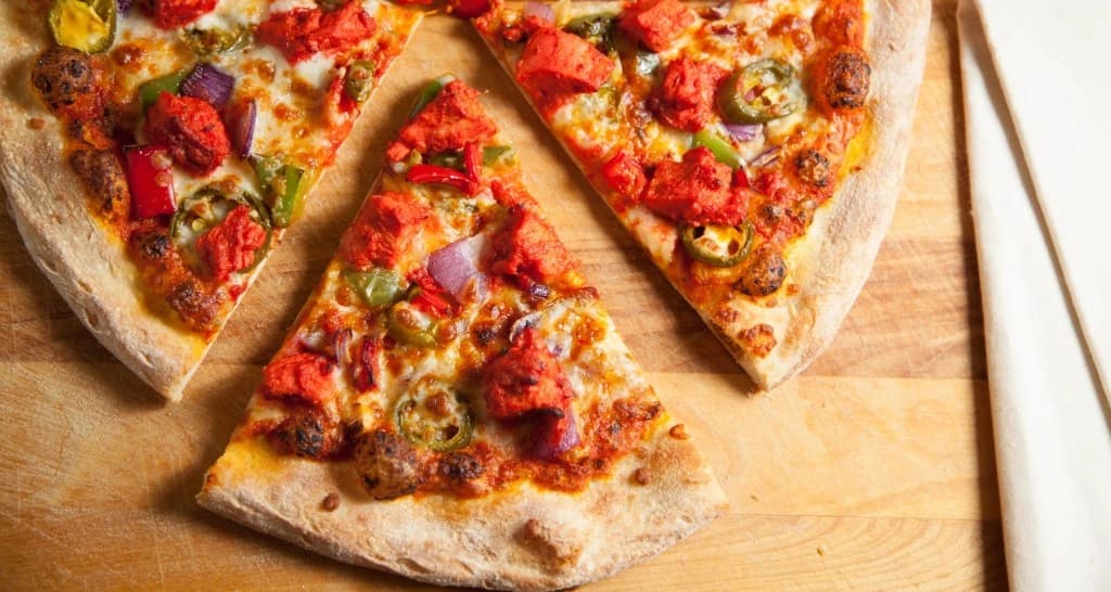 Tandoori chicken pizza topped with seasoned chicken, peppers, onions, jalapeños, and melted cheese.